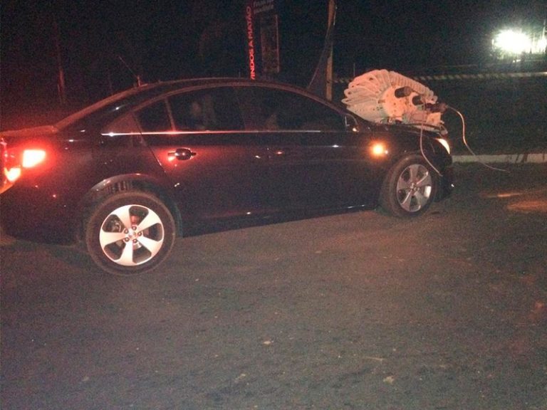 Carro bate contra um poste e transformador cai sobre o capô