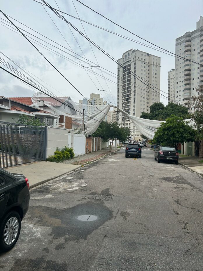 Com a ventania, tela de proteção de obra cai de prédio e atinge fiação elétrica de rua em São José Com a ventania, tela de proteção de obra cai de prédio e atinge fiação elétrica de rua em São José