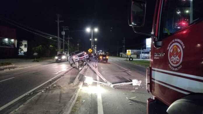 Carro fica suspenso sobre guard rail após bater em poste na SP-55, em Caraguatatuba