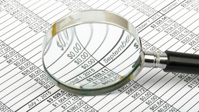 Tabela de valores com uma lupa em destaque sobre dados financeiros, representando análise de contribuições para aposentadoria por pontos.