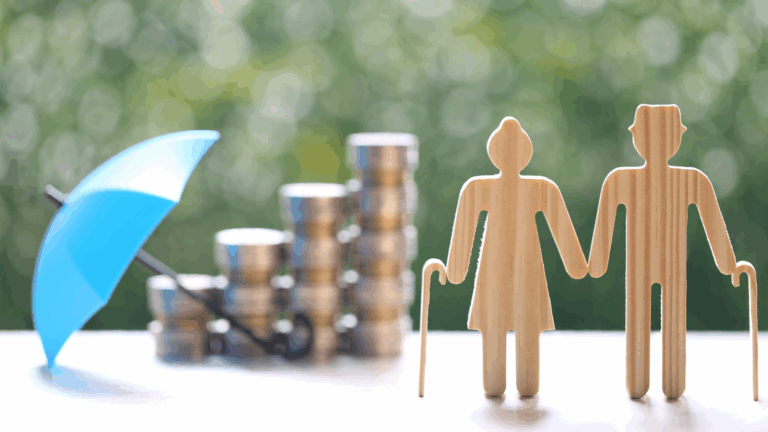 Figuras de madeira representando um casal de idosos com bengalas, ao lado de pilhas de moedas protegidas por um guarda-chuva azul, simbolizando planejamento financeiro e aposentadoria.