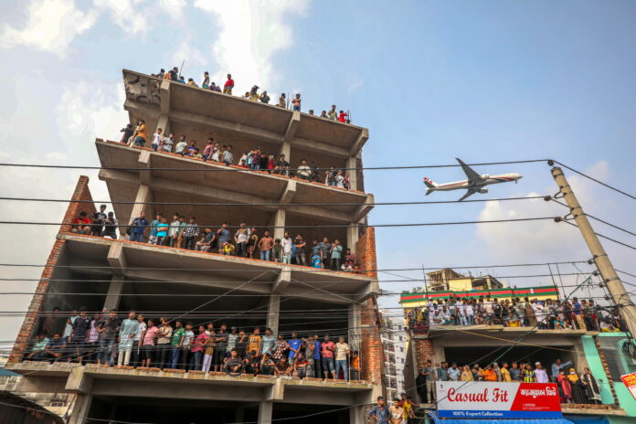 Pessoas se reúnem perto do local onde uma aeronave de treinamento da Força Aérea caiu no campus do Milestone College, em Dhaka, Bangladesh | EFE/EPA/MONIRUL ALAM