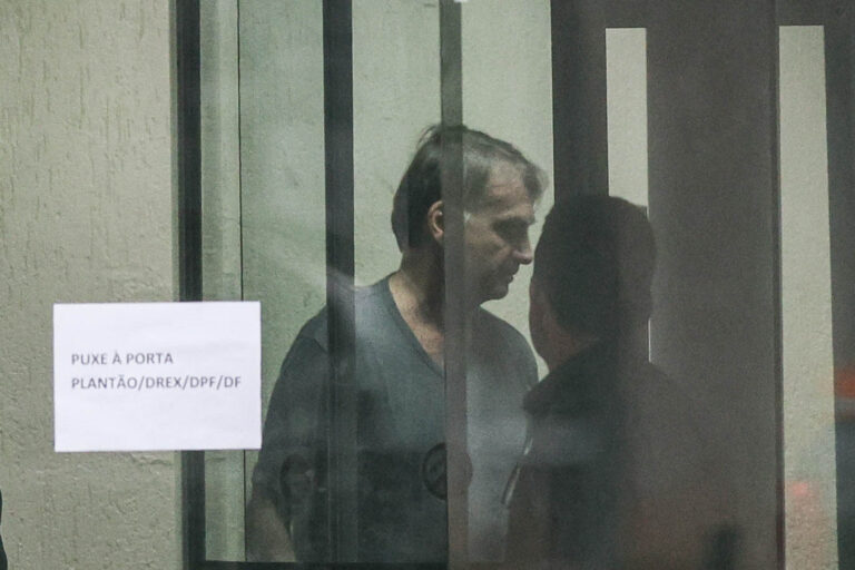 O ex-presidente Jair Bolsonaro é visto através do vidro da sede da Polícia Federal, em Brasília, durante sua permanência no local ao longo das investigações que motivaram sua condução | Foto: Gabriela Biló/Folhapress