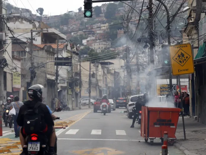 Durante operação da policia contra o Comando Vermelho, bandidos ordenaram fechamento de comércio e usaram lixeiras incendiadas para bloquear a via na rua Itapiru, no Catumbi. Foto: Fernando Frazão/Agência Brasil