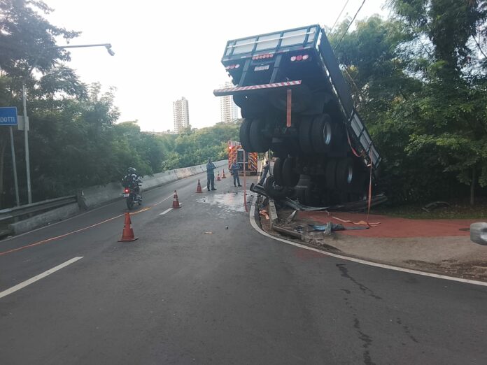 Caminhão carregado com postes de energia perde controle e cai às margens do Rio Piracicaba