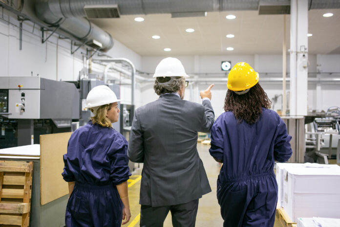 Male engineer and female factory employees in hardhats