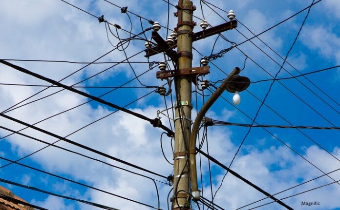 Vertical low angle shot of a lot of electricity wires under a cloudy sky